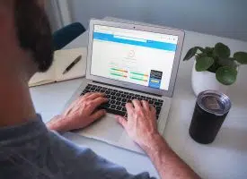 person using macbook pro on white table