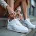 Jeune femme assise sur des marches urbaines en train de lacer ses Air Force One