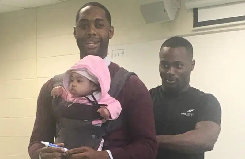 Il enseigne avec le bébé de son élève dans les bras